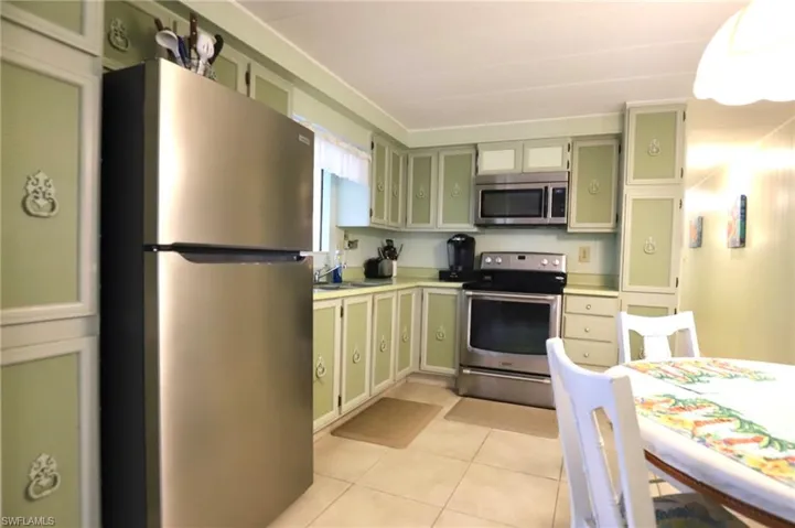 Kitchen with appliances with stainless steel finishes, light tile patterned flooring, sink, and green cabinets