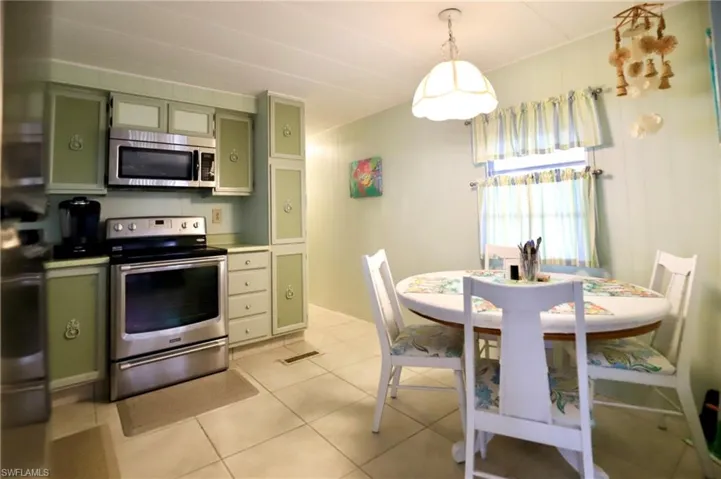 Kitchen featuring pendant lighting, green cabinetry, stainless steel appliances, and light tile patterned floors