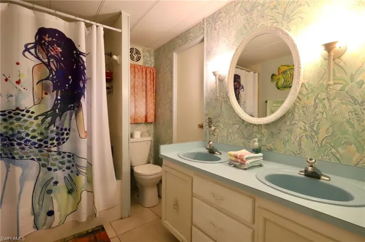Bathroom featuring vanity, toilet, a shower with shower curtain, and tile patterned floors
