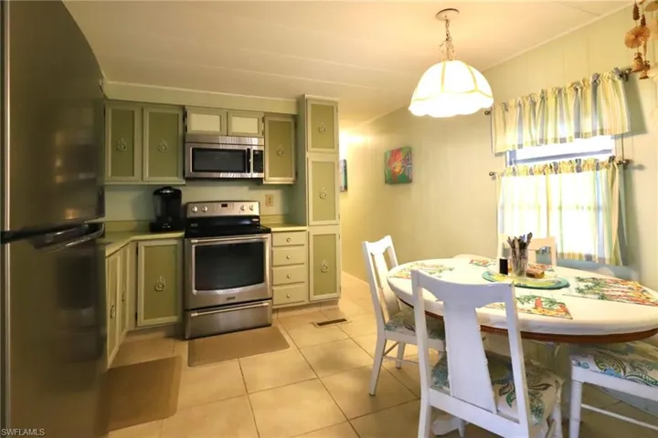 Kitchen featuring light tile patterned flooring, green cabinetry, pendant lighting, and stainless steel appliances