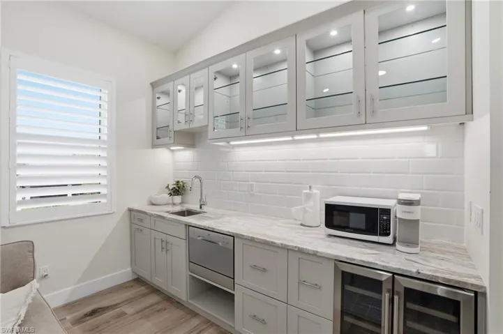 Wet bar with undercounter dishwasher, beverage center, ambient cabinetry lighting, pantry