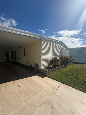View of property exterior with a lawn, concrete driveway, a patio area, and an attached carport