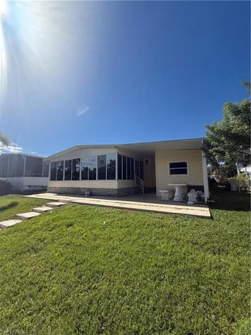 Rear view of property with a sunroom, a patio, and a lawn