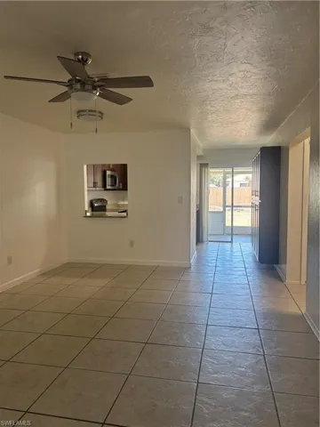 Unfurnished room with a ceiling fan, light tile patterned floors, and a textured ceiling