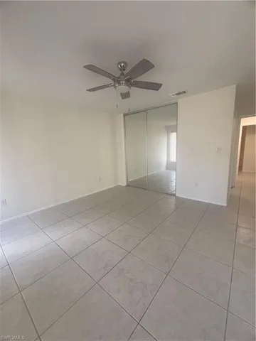 Unfurnished bedroom featuring light tile patterned floors, a closet, and a ceiling fan