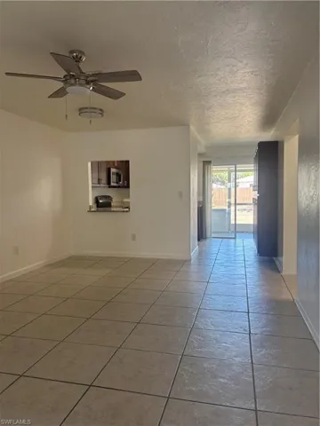 Spare room with ceiling fan, light tile patterned floors, and a textured ceiling