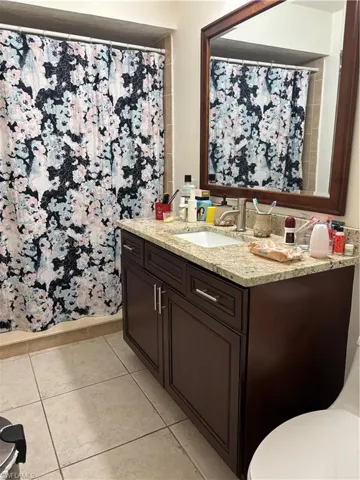 Full bathroom featuring a shower with shower curtain, light tile patterned floors, and vanity