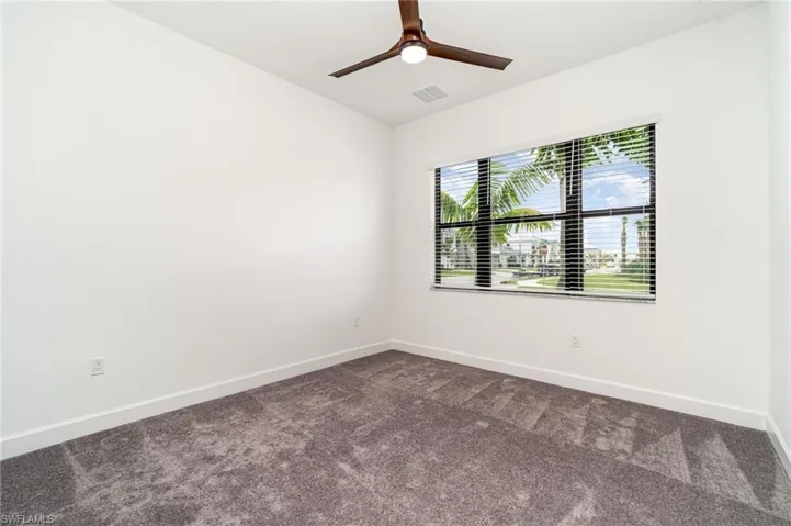Spare room featuring dark carpet and ceiling fan