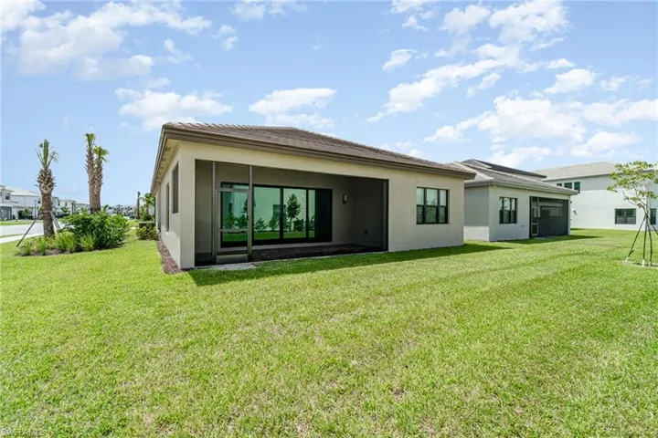 Back of house with stucco siding and a yard