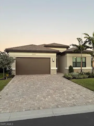 Prairie-style home featuring decorative driveway, stucco siding, an attached garage, and a tiled roof