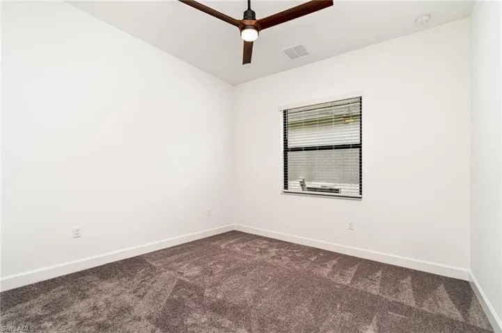 Spare room with dark colored carpet and a ceiling fan