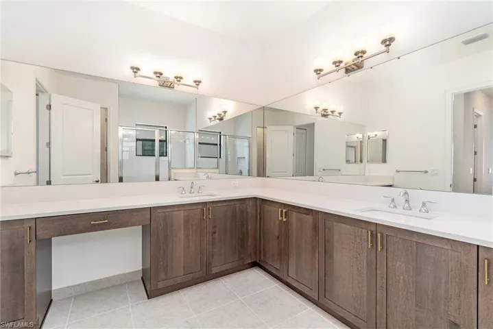 Bathroom with double vanity, a stall shower, and light tile patterned floors