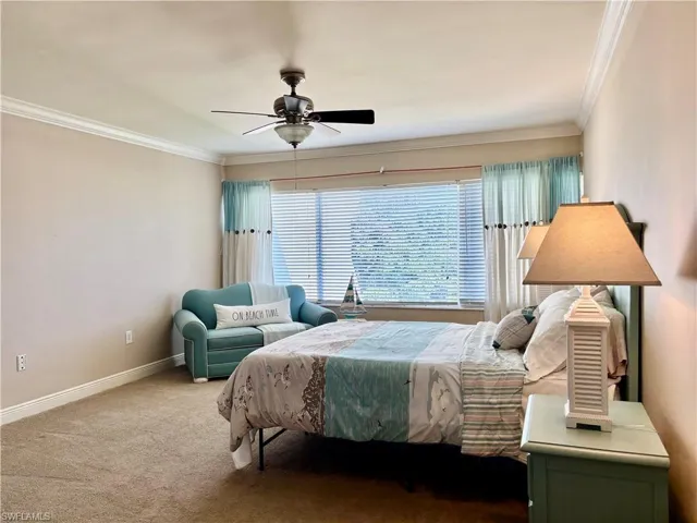 Bedroom with carpet floors, ceiling fan, and crown molding