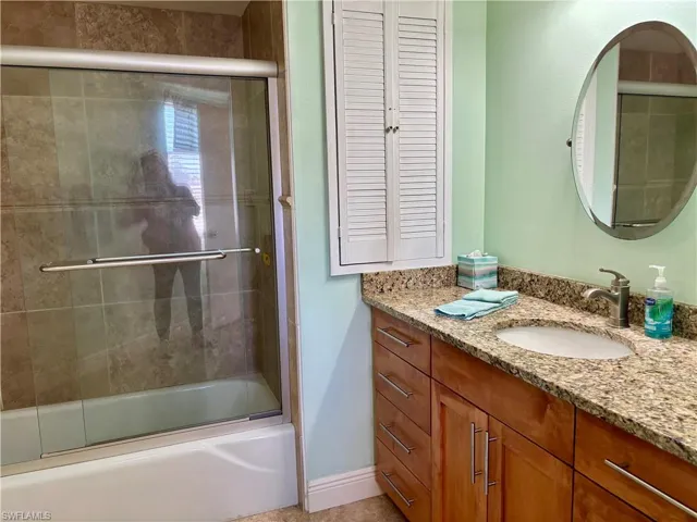 Bathroom featuring vanity and bath / shower combo with glass door