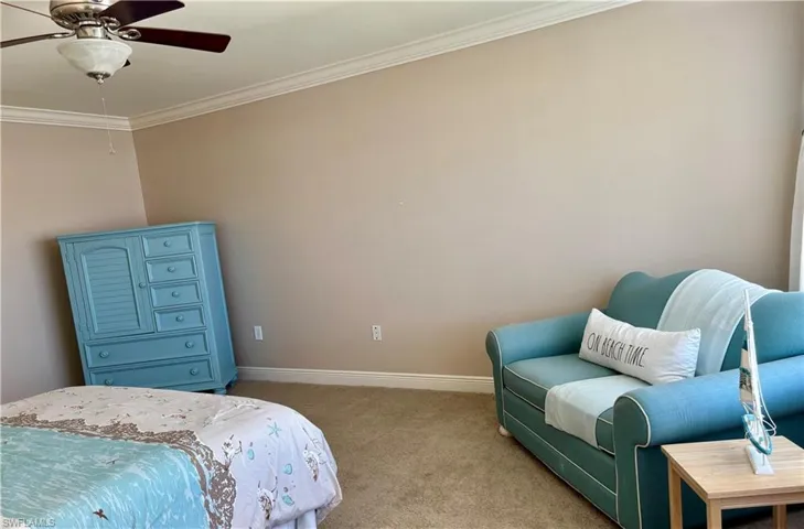 Bedroom with light colored carpet, ceiling fan, and crown molding