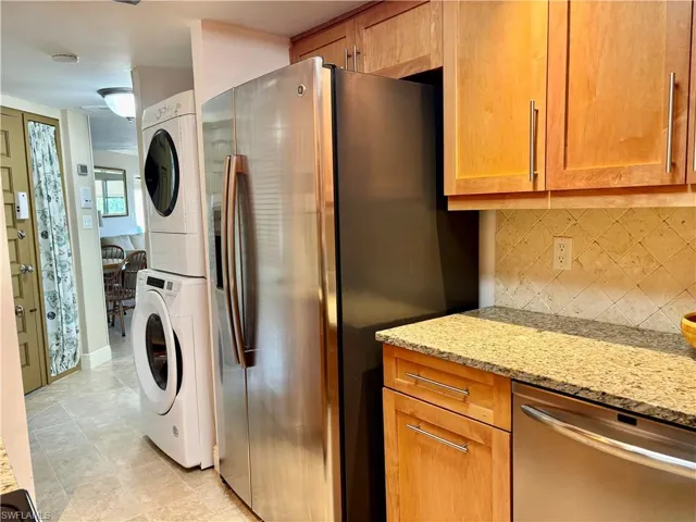 with stacked washing machine and dryer and light tile patterned flooring