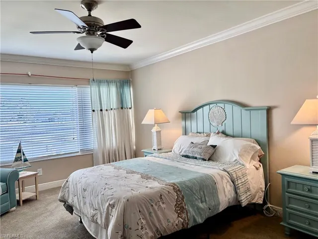Bedroom featuring ceiling fan, ornamental molding, and dark colored carpet