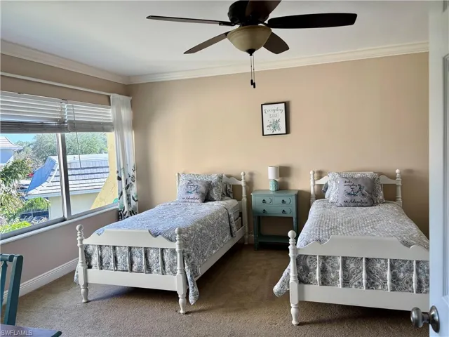 Carpeted bedroom featuring ceiling fan and ornamental molding