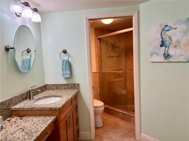 Bathroom with tile patterned floors, vanity, toilet, and a shower with shower door