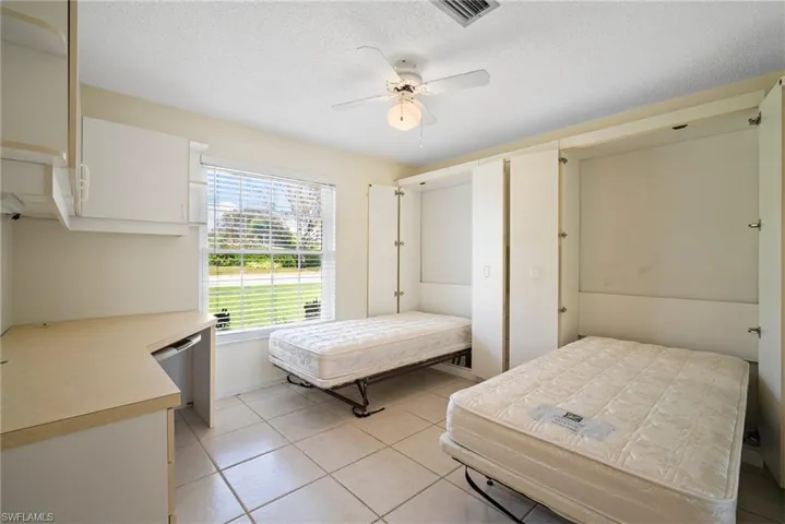 Tiled bedroom featuring a textured ceiling and ceiling fan