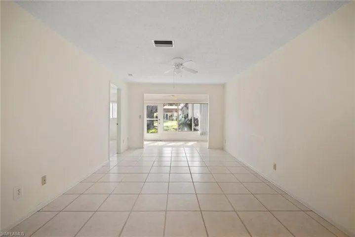 Tiled empty room featuring a textured ceiling and ceiling fan