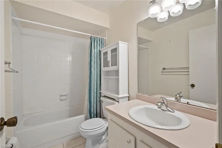 Full bathroom featuring vanity, toilet, tile patterned floors, and shower / bathtub combination with curtain