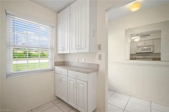 Kitchen featuring white appliances, ceiling fan, light tile patterned floors, and white cabinets