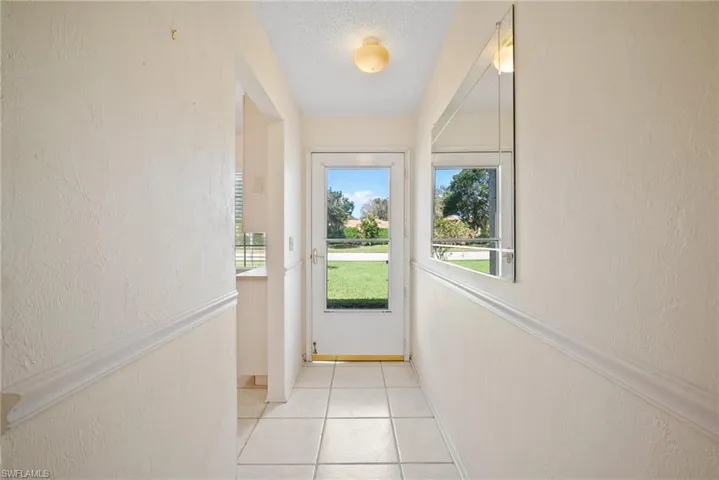 Doorway with a textured ceiling and light tile patterned floors