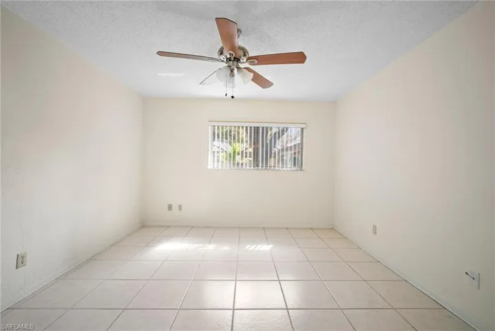 Tiled empty room featuring a textured ceiling and ceiling fan