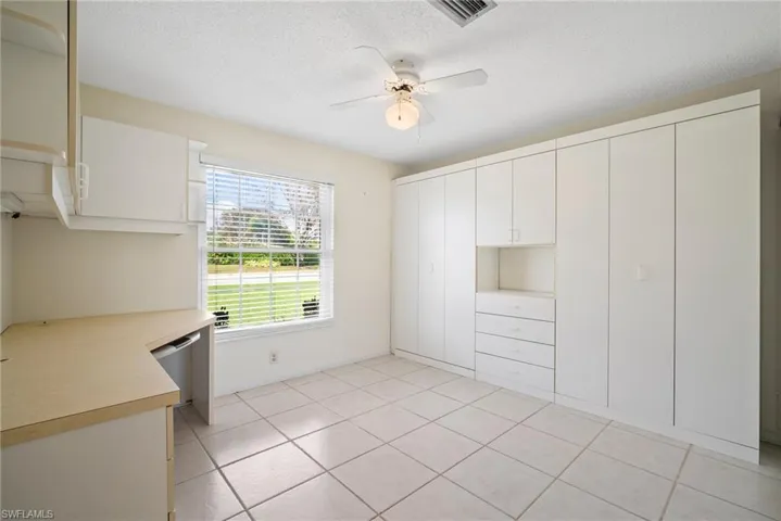 Kitchen featuring light tile patterned flooring, white cabinetry, stainless steel dishwasher, and ceiling fan