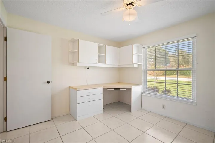 Unfurnished office with built in desk, a textured ceiling, and light tile patterned flooring