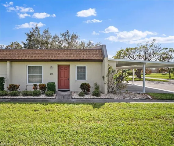 Single story home featuring a front yard and a carport