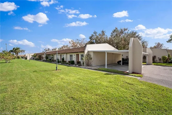View of front of property featuring a front lawn and a carport