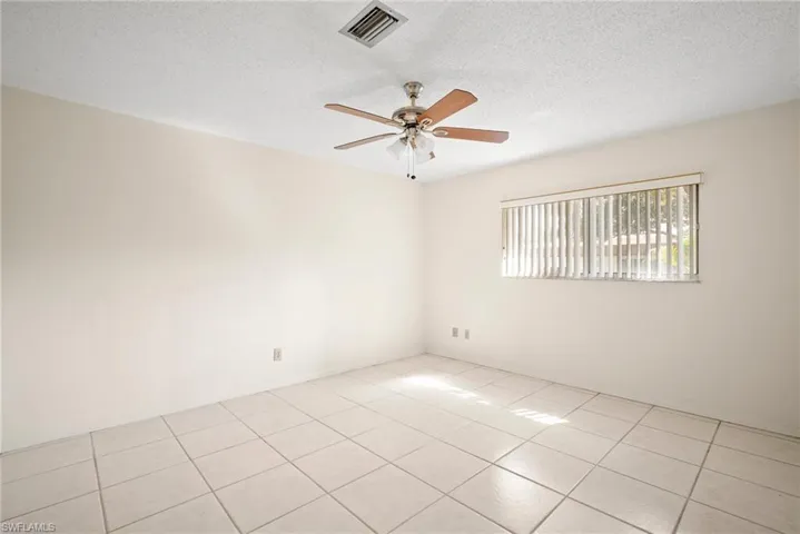 Tiled spare room with a textured ceiling and ceiling fan