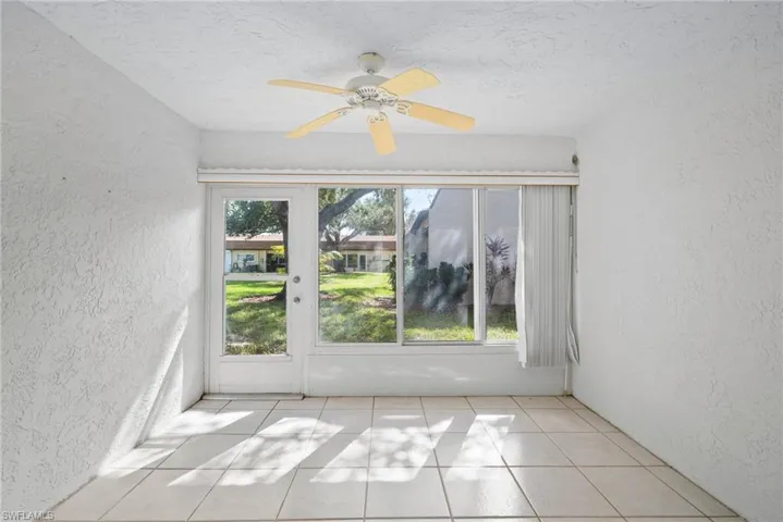 Empty room with ceiling fan, a textured ceiling, and light tile patterned flooring