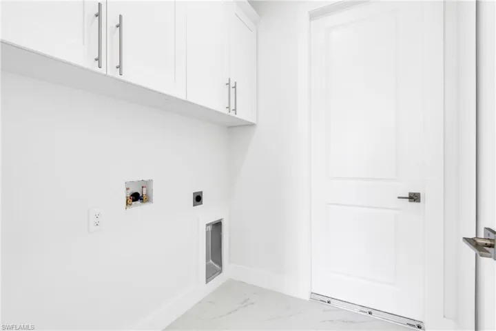 Clothes washing area with marble finish floor, baseboards, hookup for a washing machine, cabinet space, and hookup for an electric dryer