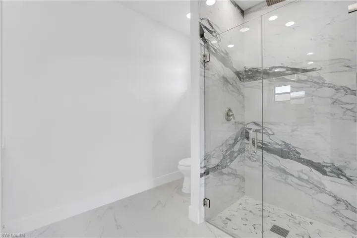 Bathroom with baseboards, toilet, marble finish floor, a marble finish shower, and recessed lighting