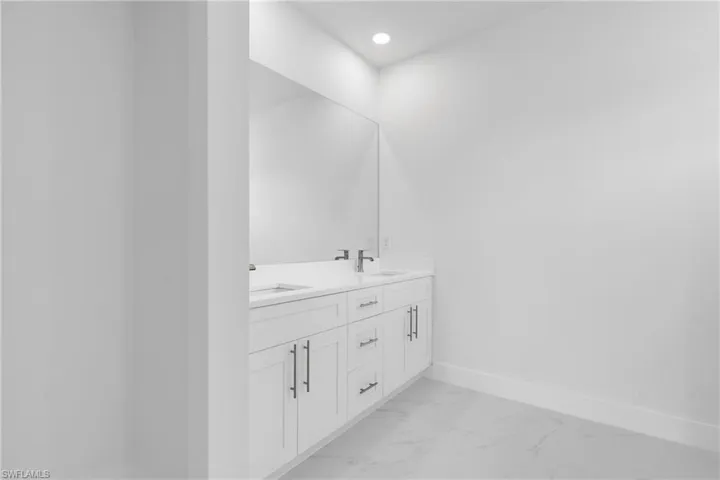 Bathroom with double vanity, baseboards, a sink, and marble finish floor