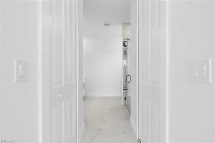 Corridor with visible vents, marble finish floor, and baseboards
