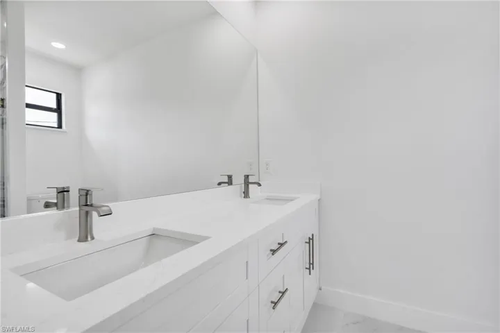 Bathroom featuring double vanity, baseboards, a sink, and marble finish floor