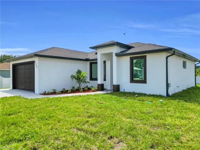 View of front of home featuring an attached garage, driveway, a front yard, and stucco siding