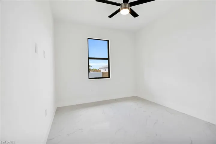 Unfurnished room featuring a ceiling fan, baseboards, and marble finish floor