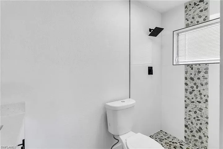 Full bath with tiled shower and toilet