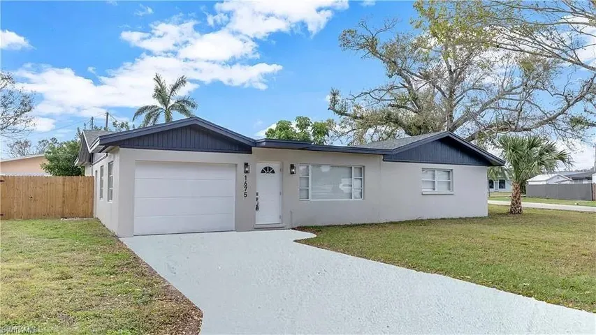 Single story home with stucco siding, an attached garage, and driveway