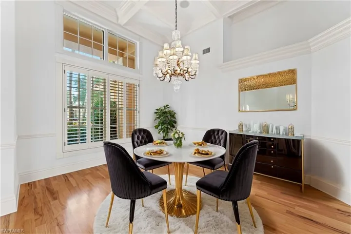 Dining area with coffered ceiling, crown molding, beamed ceiling, a notable chandelier, and wood-type flooring