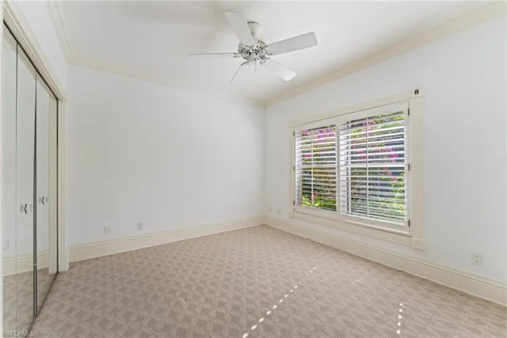Unfurnished bedroom with light carpet, a closet, ceiling fan, and ornamental molding