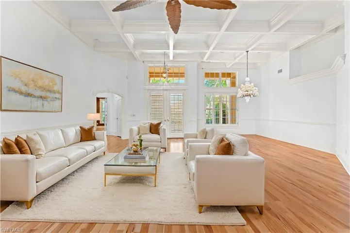 Living room with a chandelier, hardwood / wood-style flooring, beamed ceiling, and coffered ceiling