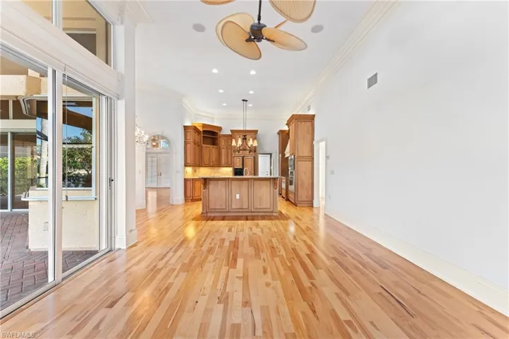 Unfurnished living room featuring ceiling fan with notable chandelier, ornamental molding, and a towering ceiling