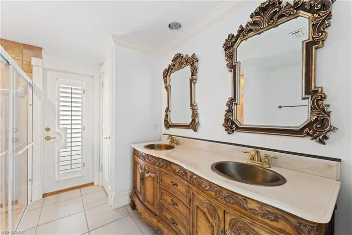 Bathroom featuring tile patterned floors, crown molding, vanity, and walk in shower