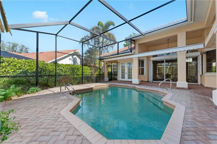 View of pool with french doors, glass enclosure, and a patio area